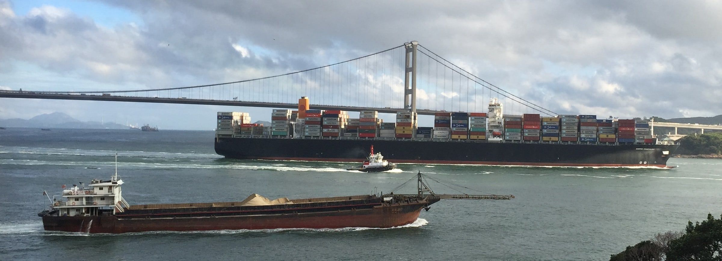 Container ship and bulk carrier passing beneath a suspension bridge - photograph by Simon Daniels