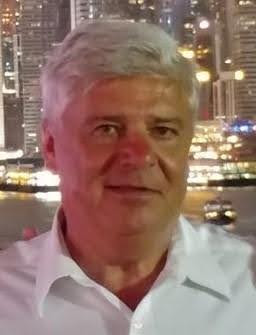 Man in white shirt smiling with city skyline illuminated at night